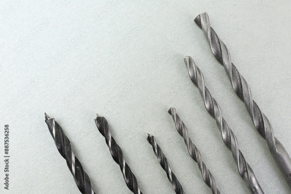 Poster Many different drill bits on light grey background, top view