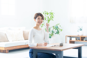 自宅で机に向かいガッツポーズをする女性