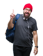 Naklejka premium Young hipster man wearing red wool cap and backpack over isolated background pointing finger up with successful idea. Exited and happy. Number one.