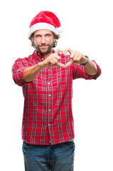 Handsome hispanic man model wearing santa claus christmas over isolated background smiling in love showing heart symbol and shape with hands. Romantic concept.