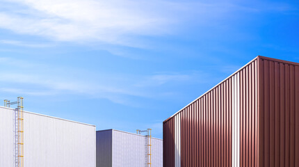 Brown corrugated metal industrial office building with 2 large production buildings in factory area against blue sky background, perspective side view