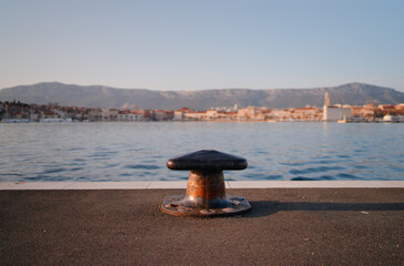 Iron bollard for mooring of ships at pier. Landscape with sea wharf. Split, Croatia.