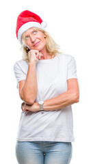 Middle age blonde woman wearing christmas hat over isolated background with hand on chin thinking about question, pensive expression. Smiling with thoughtful face. Doubt concept.