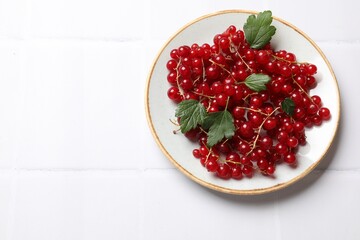 Fresh red currants and green leaves on white table, top view. Space for text
