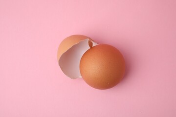 Pieces of broken eggshells on pink background, above view