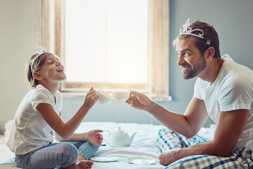 Dad, girl and fun tea party in home with smile, cheers for bonding with fantasy, tiara and support in bedroom. Growth, development and happy man with daughter on bed playing princess game in morning © NonVig/peopleimages.com