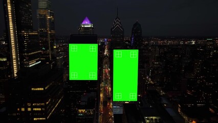 Green screen graphic on dark skyscrapers in American city at night. Billboards with tracking points. Aerial