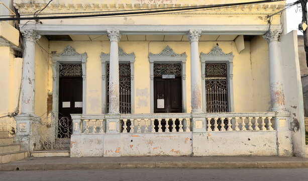 One-storey Colonial house facade featuring creamy-yellow wall and Corinthian column-supported entrance porch, Calle Clarin Street. Santiago-Cuba-512