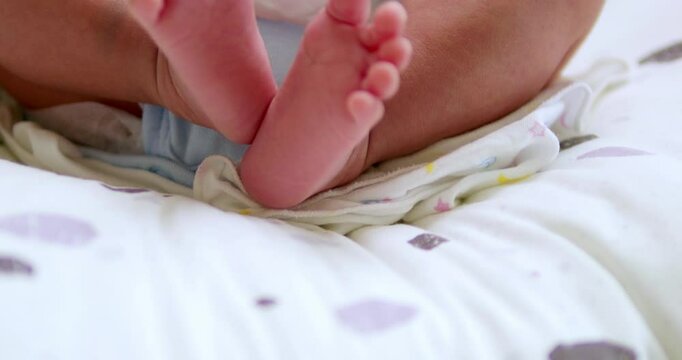 A baby's tiny feet are kicking and stretching as it is lying on its crib inside the nursery.