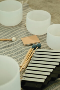 Sound bath instruments arranged on a striped cloth mat.