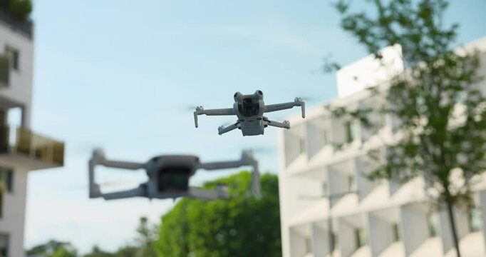 Mini quadcopter drones flying at mid-air with cityscape in background