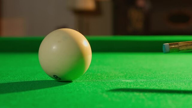 Close up shot of russian billiard green cloth table with white ball being hit by the cue, person hitting the ball away from scene.