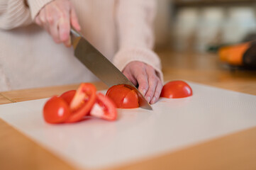 Woman cutting fresh tomato, close up shot