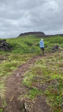 woman with a camera in her hands goes to Eldborg crater in Iceland
