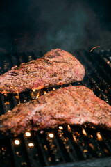 Tri tip meat cooking over open flame on a grill