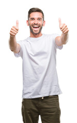 Young handsome man over isolated background approving doing positive gesture with hand, thumbs up smiling and happy for success. Looking at the camera, winner gesture.