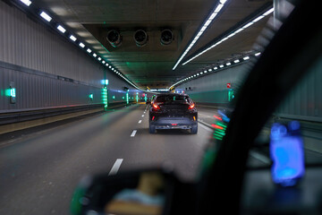 City road tunnel with cars on the road and artificial lighting.