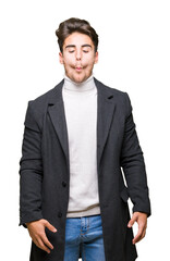 Fototapeta premium Young elegant man wearing winter coat over isolated background making fish face with lips, crazy and comical gesture. Funny expression.