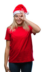 Young caucasian woman wearing christmas hat over isolated background doing ok gesture with hand smiling, eye looking through fingers with happy face.