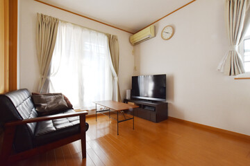 Modern Living Room Interior with Large Window, Black Sofa, and TV（大きな窓と黒いソファーとテレビがある明るいリビングの室内）