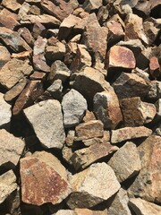 Close-Up View of a Rustic, Sunlit Stack of Varied Earth-Toned Rocks and Stones, Showcasing Natural Textures and Patterns