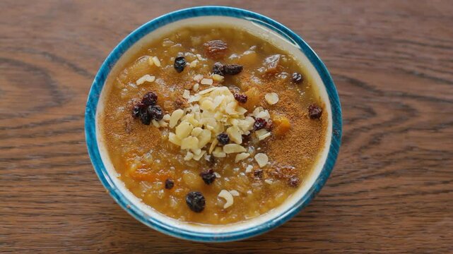 Putting a bowl of Ashure dessert on a table. Traditional delicious Turkish dessert.