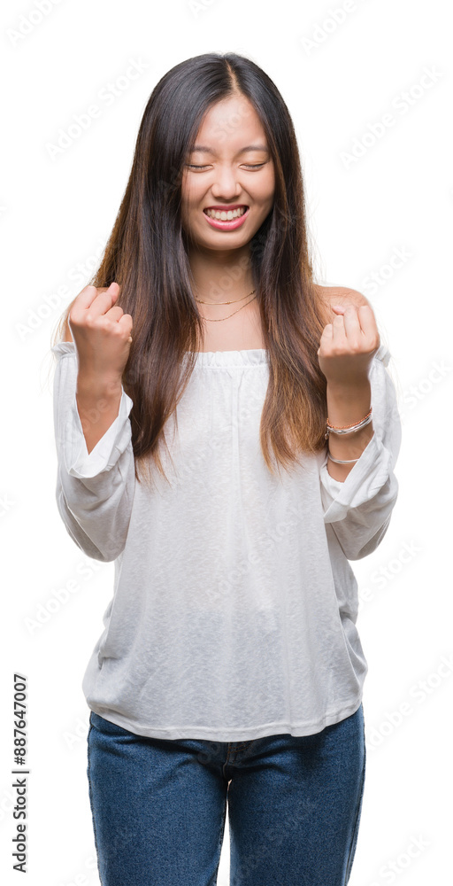 Canvas Prints Young asian woman over isolated background very happy and excited doing winner gesture with arms raised, smiling and screaming for success. Celebration concept.