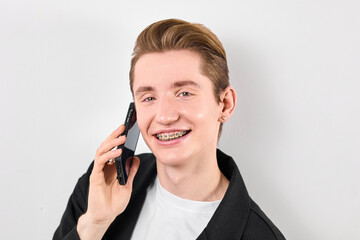A man is standing while holding a cell phone to his ear, engaged in a phone conversation. He appears focused and attentive as he communicates through the device