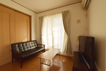 Modern Apartment Living Room with Large Window and Black Sofa（大きな窓と黒いソファーがあるフローリングのアパートのリビング）
