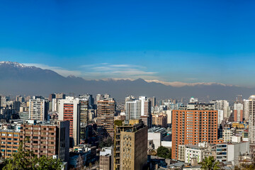 Distant snow-capped Andes mountain range beyond urban skyline.