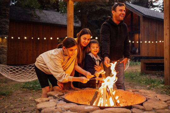 A young married couple with children roasts marshmallows on the fire.