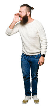 Young hipster man wearing winter sweater shouting and screaming loud to side with hand on mouth. Communication concept.