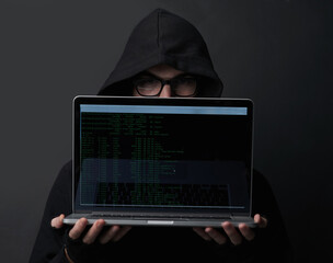 Man, hoodie and hacker in studio, laptop and fraud of cybersecurity, online and glasses with screen. Black background, crime and coding of criminal, programming and ransomware with error and person