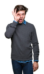 Young handsome elegant man over isolated background doing ok gesture shocked with surprised face, eye looking through fingers. Unbelieving expression.