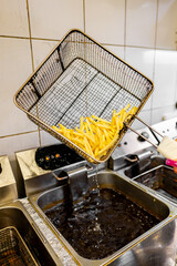 A busy commercial kitchen with a deep fryer cooking French fries