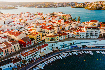 Aerial view of Es Castell traditional town on the Menorca coast with harbor and boats at sunset...
