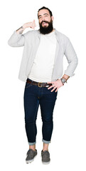 Young man with long hair, beard and earrings smiling doing phone gesture with hand and fingers like talking on the telephone. Communicating concepts.