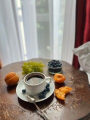 Breakfast in bed. Cup of coffee with fresh fruits on a wooden table in a hotel room.