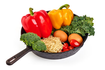 Vegetables with egg Noodles on a cast iron frying pan, isolated on white background.