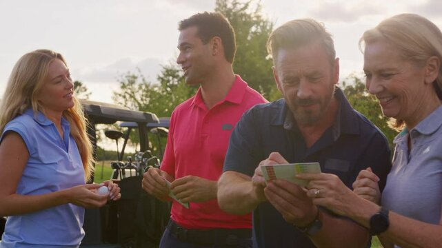 Mature and mid adult couples standing by golf buggy checking score cards together -= shot in slow motion