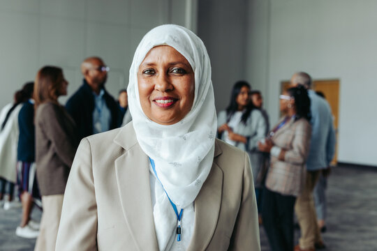 Muslim businesswoman in hijab attending a conference with colleagues in the background