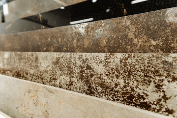 The photograph displays various stains on a marble countertop, possibly from substances such as automotive tires, wood, and asphalt, creating a detailed view of the damage