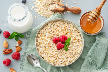 Bowl of porridge or oatmeal with fruits, nuts and honey. Breakfast cooking.