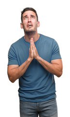 Handsome young casual man begging and praying with hands together with hope expression on face very...