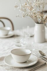 Fototapeta premium Ceramic bowl on a plate with dried flowers in the background on a dining table. Minimalist photography. Rustic dining concept. Design for interior, poster, wallpaper. Closeup with copy space.