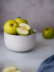 Vertical Photo of Green Apples in Ceramic Plate on Concrete Background with Sliced Apple on Top. High quality photo