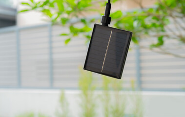 Small solar battery cell panel hanging from the tree in the garden at home.