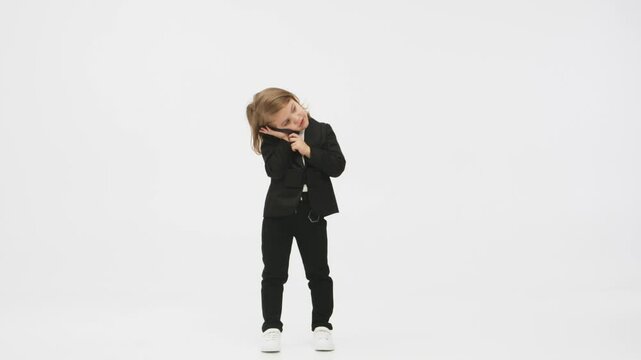 Concept of business, deal and modern technology. Little business girl on a white background in the studio presses her mobile phone and shows a &ldquo;super&rdquo; gesture of approval.
