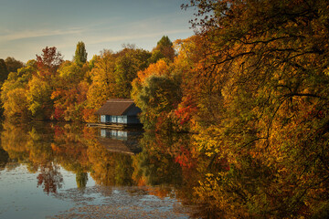 Landscape with beautiful house on a lake with colourful leafs in autumn season