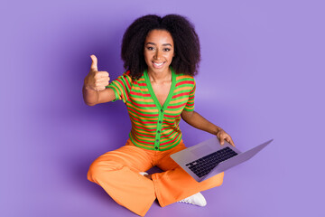 Full length photo of adorable lovely girl wear striped shirt typing modern device showing thumb up empty space isolated violet color background